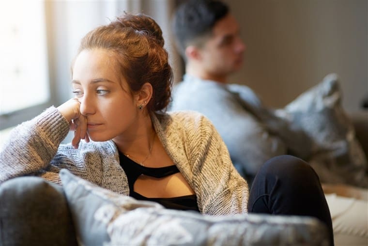 Stressed woman looking away from partner who is not paying attention.